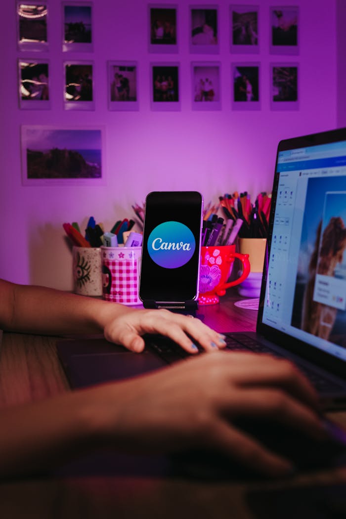 gallery-1 A creative home workspace with a laptop and smartphone displaying Canva, showcasing a vibrant, organized desk setup.