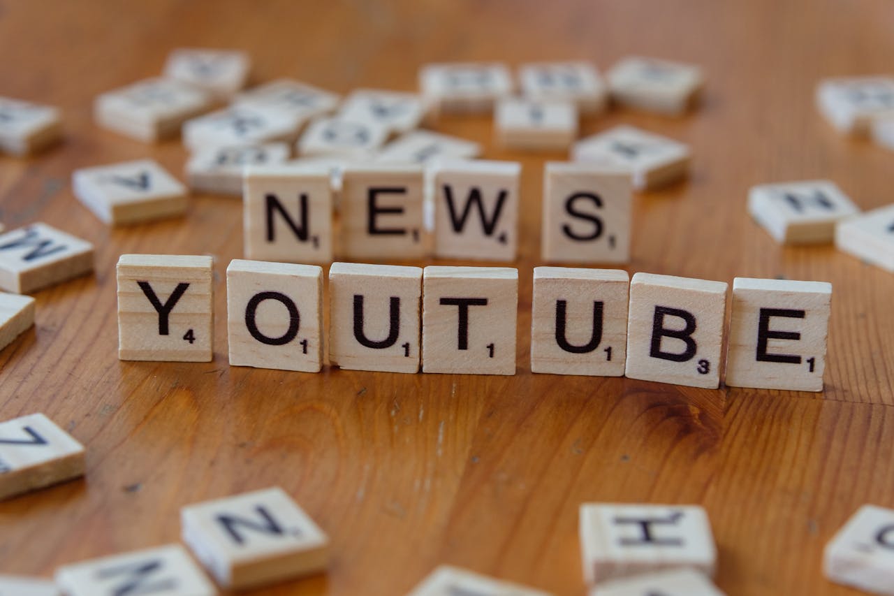 gallery-5 Scrabble tiles spelling words on wooden surface, focusing on YouTube and News.