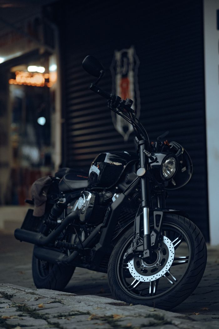 gallery-1 Dark motorcycle parked on a city street in Fethiye, Türkiye, showcasing its sleek design.