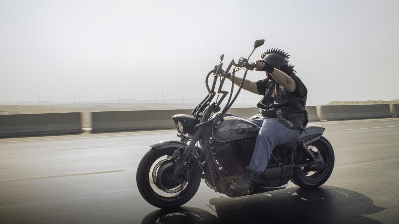 services-01 Rider on a custom motorcycle cruising down a highway, showcasing freedom and adventure.