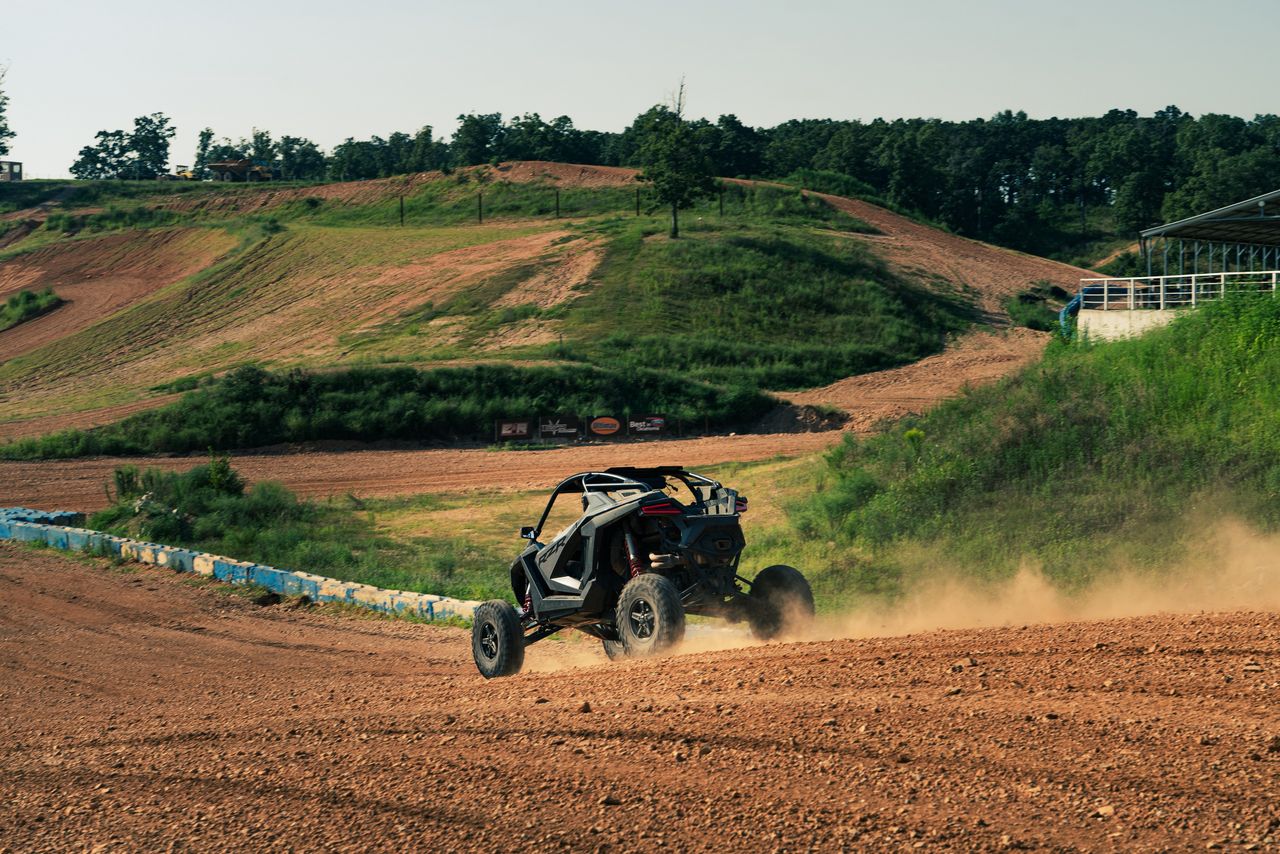 gallery-4 Action-packed ATV racing scene on a dusty track in Jay, Oklahoma, with scenic green hills.