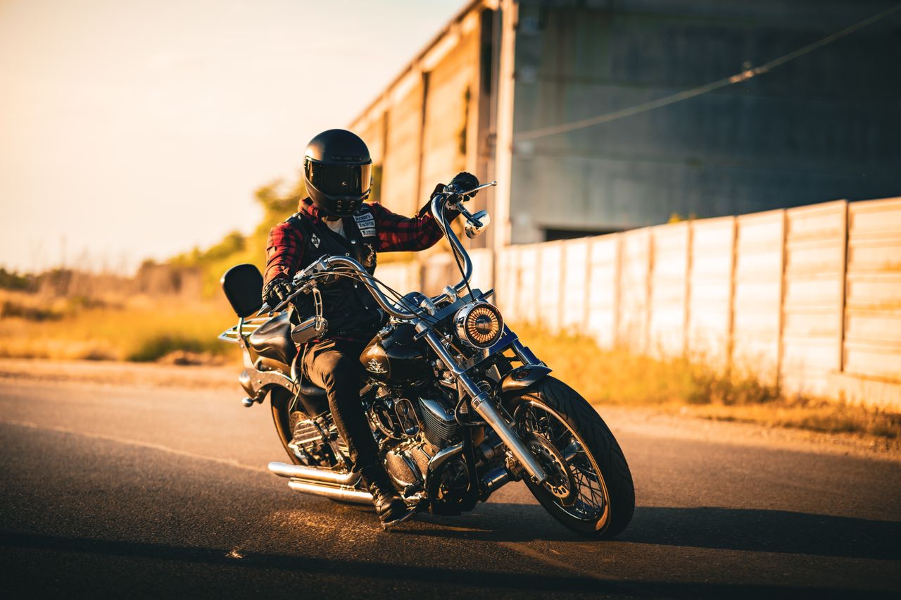 about-01 Biker rides a cruiser motorcycle on an open road during sunset, showcasing adventure and freedom.