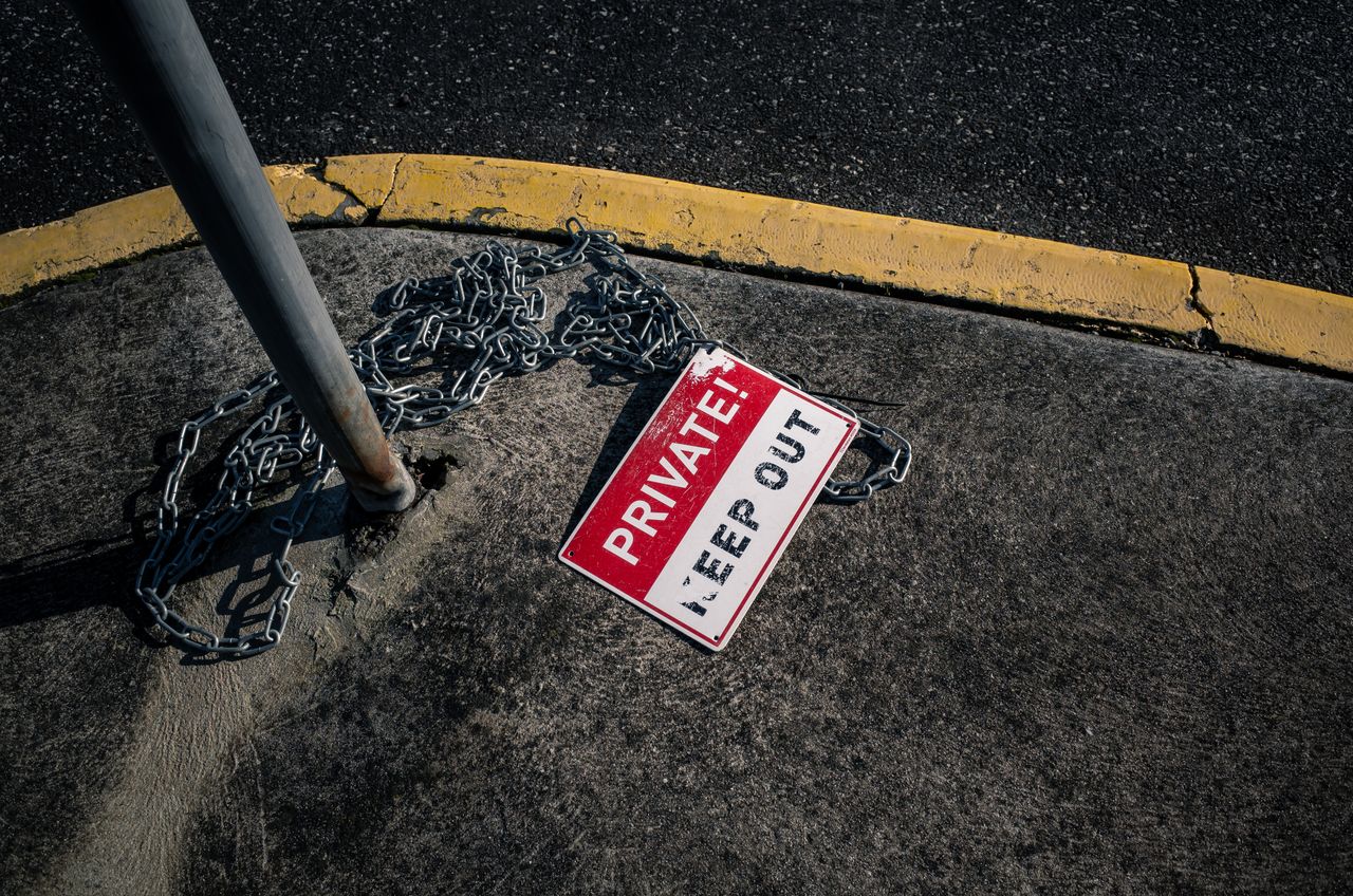 hero-img-02 A chained 'Private Keep Out' sign lies on an urban sidewalk, emphasizing security.